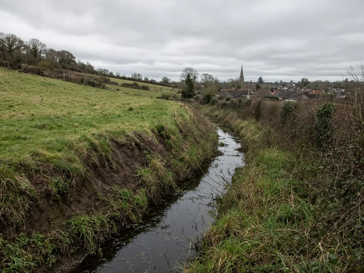 Drainage ditch and sloping field on the edge of a UK village
